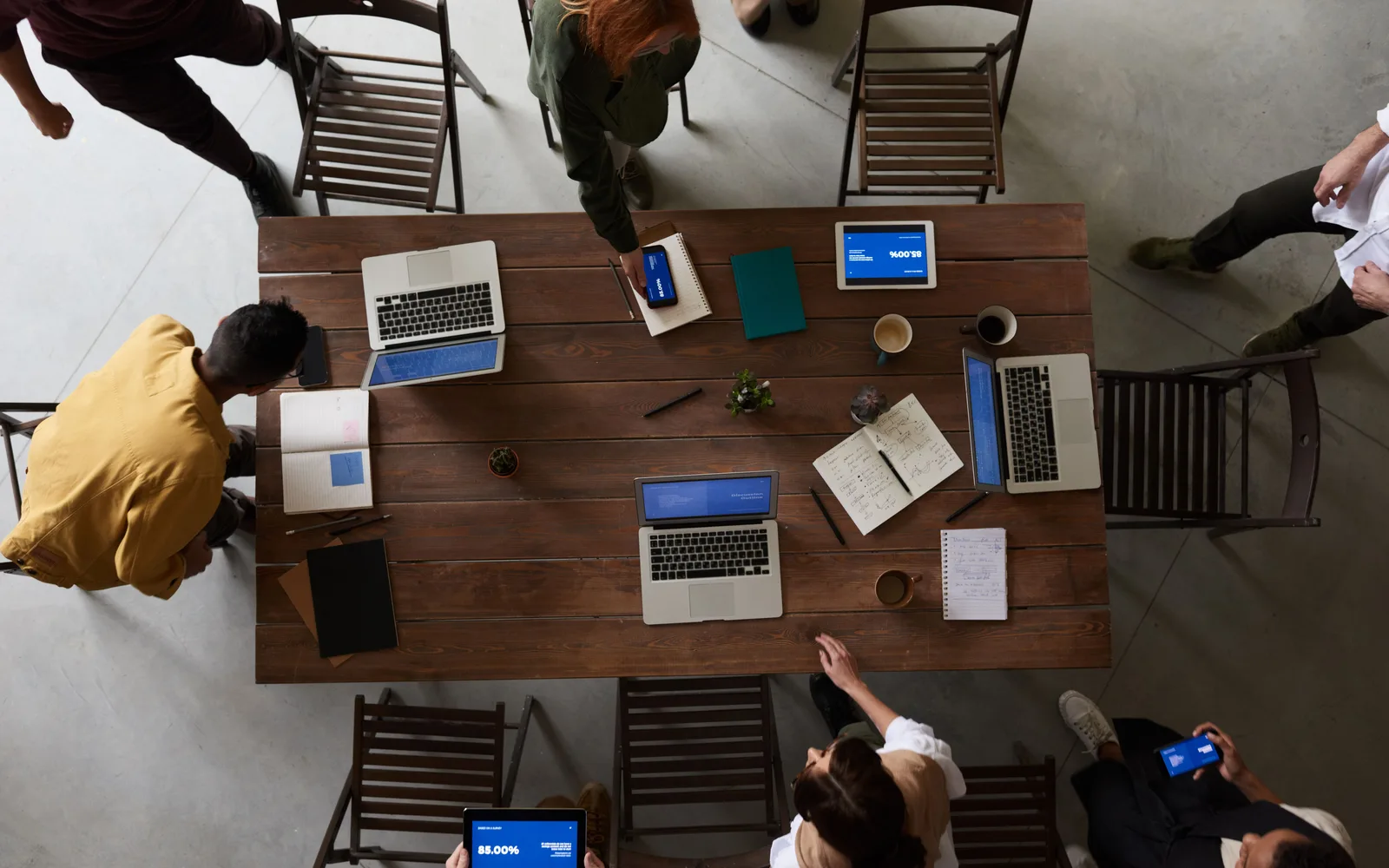 Overhead view of people working around a table with laptops and notebooks